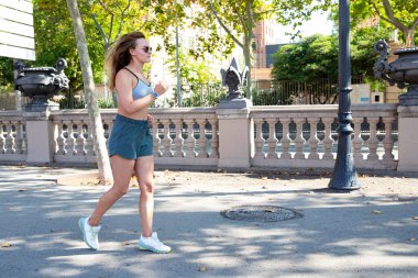 Yaz parkında yürüyen bir bayan sporcu. Açık havada zinde bir kadın