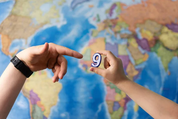 Adult and child hands holding numbers plastic toy on the world political map background. Travel planning explore destination concept. Family holidays and time together. Quarantine over, borders open