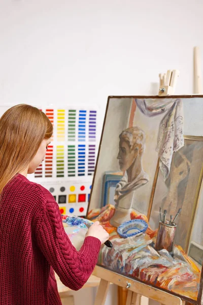 Classes in art school. The girl draws a large picture of oil paints. Courses of drawing for adults.