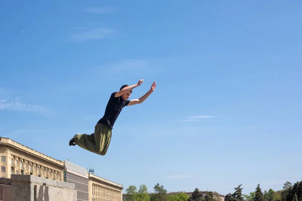 A young man is jumping from the wall. Parkour in the urban space. Sports in the city. Sport activity.