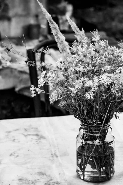 Cute wildflowers bouquet in a glass jar in black and white