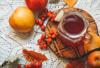 Beyaz bir açık peçete üzerinde sarı yapraklar, elma ve kırmızı çilek Sonbahar kompozisyon, bir cam kupa kırmızı komposto, sonbahar natürmort
