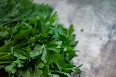 Koyu, eski bir ahşap arka planda yeşil baharatlı dereotu ve maydanoz, çözünmüş fotoğraf, bulanık arkaplan; koyu bir arka planda yeşil çimenlerin soyut kompozisyonu, ev tariflerinde pişirme