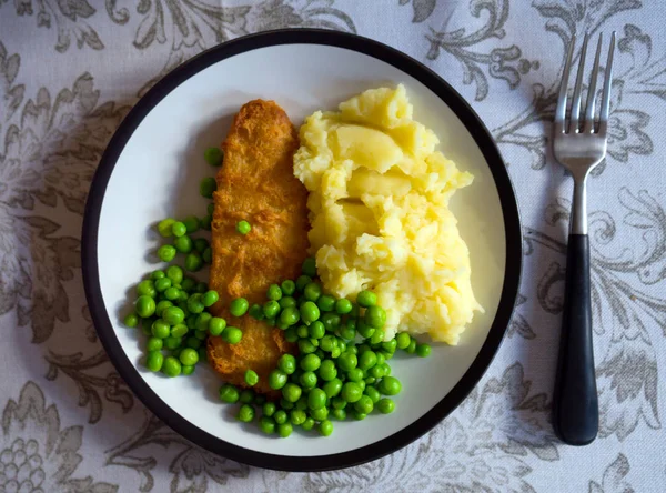 Ugnsbakad fiskfilé med potatismos och gröna ärtor, traditionell brittisk måltid Stockfoto