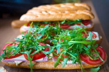 Jambon, peynir, domates ve yabani roket ile taze denizaltı baget sandviç. Seçici odaklama.