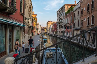 Gondolcu gondolunu çekiyor ve İtalya, Venedik 'te alçak bir köprünün altından geçmeye hazırlanıyor.
