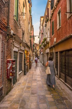 Gondolcu gondolunu çekiyor ve İtalya, Venedik 'te alçak bir köprünün altından geçmeye hazırlanıyor.