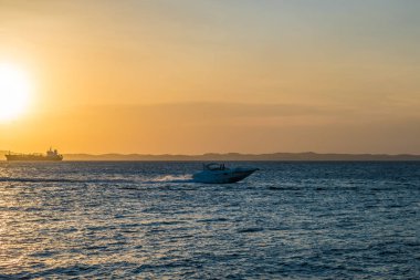 Brezilya, Salvador 'daki tüm azizlerin körfezinde gün batımında yelken açan bir sürat teknesi.