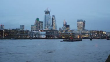 Londra İngiltere - 04.04.2022: Londra Köprüsü de dahil olmak üzere şehir gökdelenleri Thames nehri boyunca finans bölgesi manzarasını aydınlatıyor. Ayrıca 20 Fenchurch, Lloyds binası, willis Binası ve Heron Kulesi ve 100 Bishop Geçidi de dahil olmak üzere ünlü binalar.