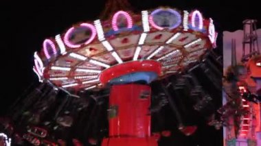 Panayır alanı salıncak sürüşü gökkuşağı ışıkları insanları salıncakta sallıyor.