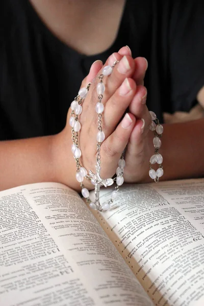catholic praying hands with bible and rosary beads background