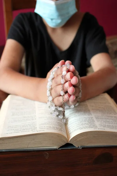 catholic praying hands with bible and rosary beads background