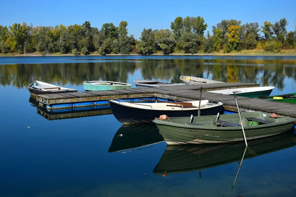 Bir gölü, bir tekne köprüsü ve birkaç teknesi olan sonbahar manzarası.. — Stok fotoğraf