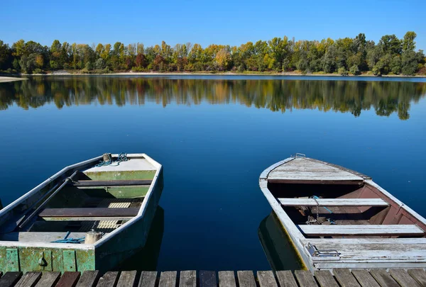 Herbstlandschaft mit See, Bootsbrücke und zwei Booten. — Stockfoto