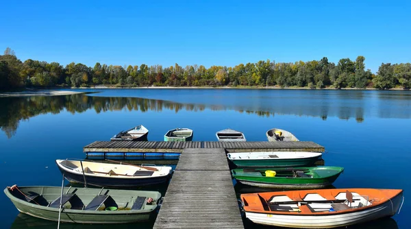 Herbstlandschaft mit See, Bootsbrücke und einigen Booten. — Stockfoto