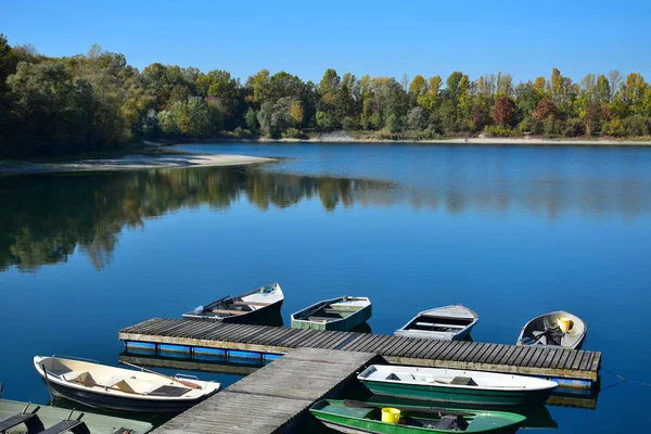 Paisagem de outono com um lago, uma ponte de barco e alguns barcos . — Fotografia de Stock