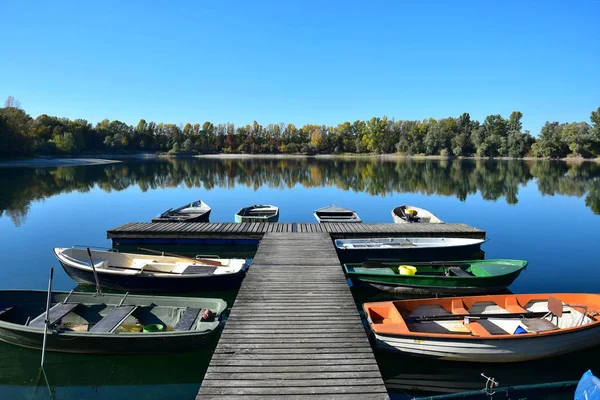 Herbstlandschaft mit See, Bootsbrücke und einigen Booten. — Stockfoto