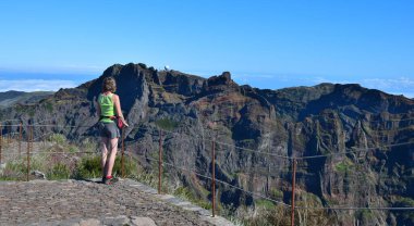 Pico Ruivo dağının zirvesinde duran bir kadın, radar istasyonuyla Pico do Arieiro 'ya bakıyor. Madeira, Portekiz.