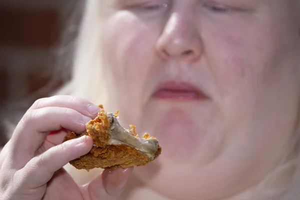 Женщина, поедающая куриное бедро — стоковое фото