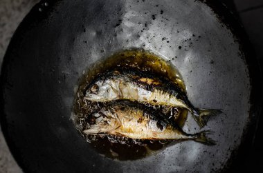 Yakından kapatın. Tavada balık. Asyalılar sabahları mutfakta yemek pişirirler..