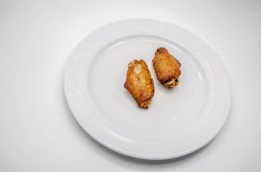 Yakından kapatın. Beyaz tabakta kızarmış tavuk kanatları.