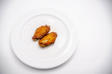 Yakından kapatın. Beyaz tabakta kızarmış tavuk kanatları.