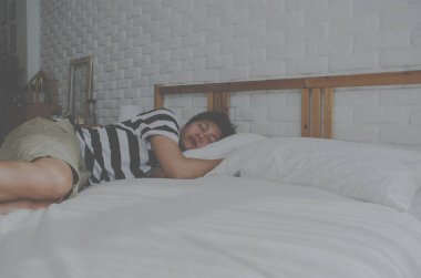 Asyalı adam beyaz bir yatak odasında uyuyor. Adam beyaz bir yatak odasında yatakta iyi uyuyor. Odada rahatlayın.