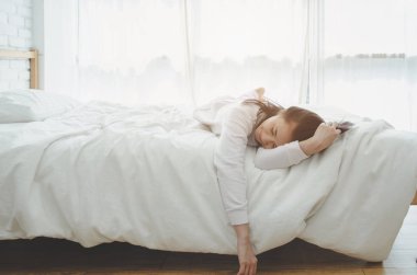 Beyaz odadaki yatakta. Yatak odasında uyuyan güzel bir kadın. Asyalı kadınlar iyi uyur. Beyaz bir odada uyumak sizi rahat hissettirir. Sıcak ton.