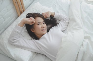 Kadınlar yatağın kenarında oturup. Ve sabah ları rahatlamak için kollarını esnetiyor. Sabah uyan. Uyandıktan sonra esneme. Sıcak bir ton. Nesneye odaklanma.