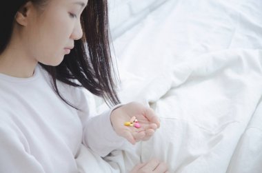 Asyalı kadın pembe tablet ile ilaç alarak giyiyor