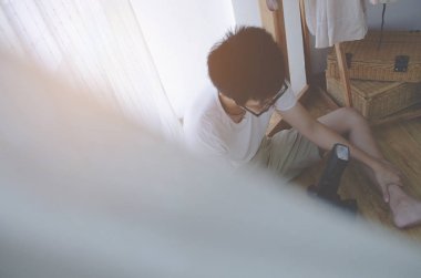 Erkekler odada yatağın kenarında oturuyor ve stres var. Beyaz gömlek giyen ve iki eliyle kafasında genç bir adam. Acı yüzünden..