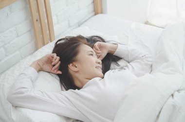 Kadınlar yatağın kenarında oturup. Ve sabah ları rahatlamak için kollarını esnetiyor. Sabah uyan. Uyandıktan sonra esneme. Sıcak bir ton. Nesneye odaklanma.