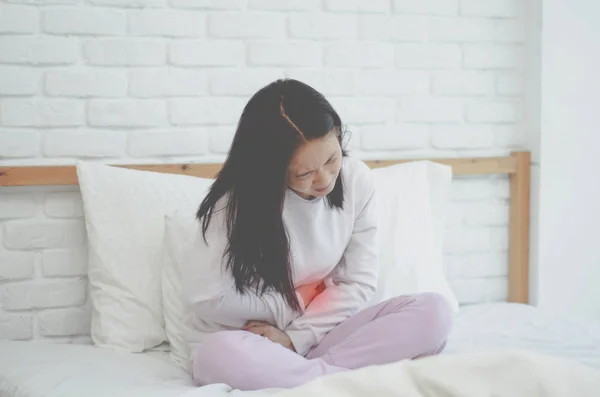 アジアの女の子は腹痛を持っており 症状を緩和するために温水袋の抱擁を使用しています — ストック写真