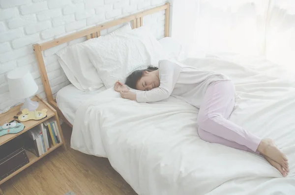 On the bed in the white room.Beautiful woman sleeping in the bedroom.Asian women sleep well.Sleeping in a white room makes you feel comfortable.Warm tone.