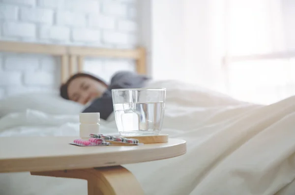 Asian women sick Lie on the white bed in the room in the morning.In the bedroom there was a lady sleeping in it.Girl are not comfortable.Warm tone.