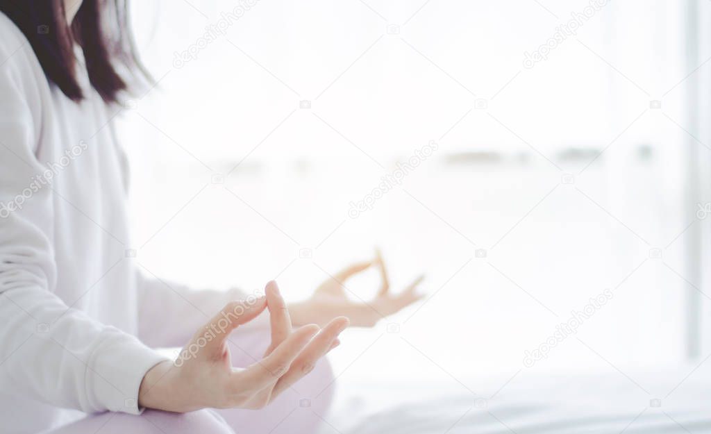 Asian girls sitting on yoga poses in bed in a warm morning.Warm tone.Do not focus on objects.