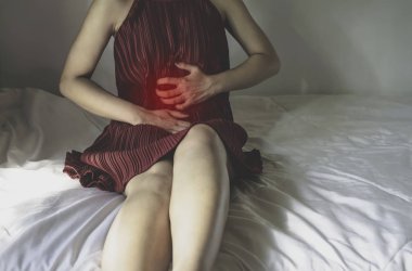 Asyalı kız karın ağrısı var. Kız şiddetli acı çekti. Menstruasyon ne zaman. Beyaz yatak odasında kız uyuyor çünkü rahat değil. Nesnelere odaklanmayın