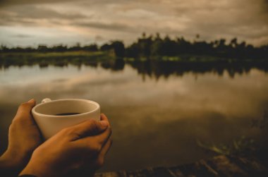 Beyaz kahve fincanı sabahları rıhtımda. Sabah kahvesi. Nesnelere odaklanma. Sıcak ton.
