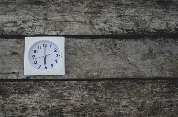 White clock on the wooden floor in the morning.On the floor there is a watch on it.