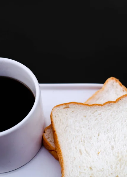 白いパンとグラスをテーブルの上に置きました 朝食テーブルの上にはグラス1杯のコーヒーとパンの盛り合わせがありました 朝はウッドフロアの朝食 — ストック写真