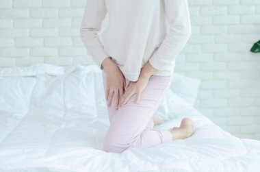 Pembe pantolonlu kadın vajinası kaşınıyor. Kadının eli bacaklarının arasına yerleştirilmiş. Vajinasında kaşıntı var..