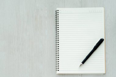 Kitabın yere siyah bir akıllı telefon yerleştirilmiş siyah bir kalemi var. Boş alanı kopyala.