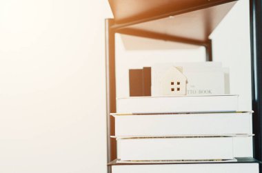 Küçük bir ev ve odada yerde bir kitap. Yerde beyaz tencereler var. Gözlükleri yerleştirin. Objeye odaklanmayın..