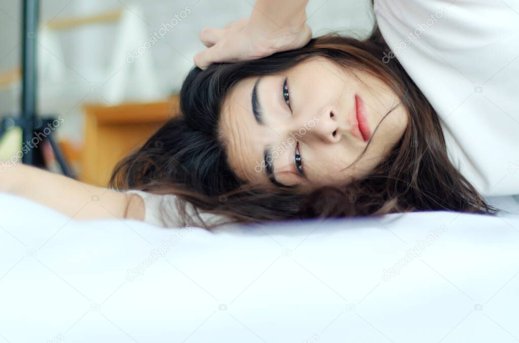 Asian woman is in a white bedroom. She is sleepy.A girl on the bed.