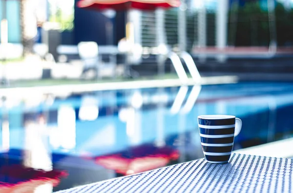 Blue coffee cup Put on a table by the pool in the morning.