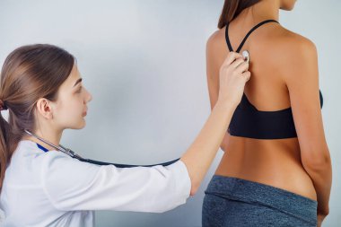 Doktor bir kadın hastanın stethoscop ile nefes kontrol. Doktor hastanın yanında oturuyor ve organizmasındaki gürültüyü steteskop la dinliyor. Close.