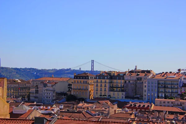 25 апреля мост (Ponte 25 де abril) через реку Техо, видели из Alfama, старый город в Лиссабоне — стоковое фото