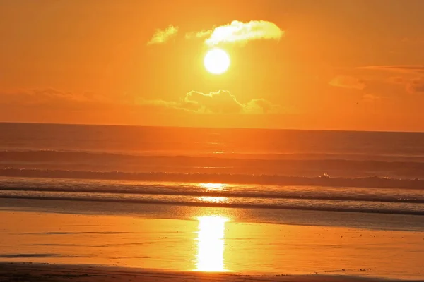 Puesta de sol naranja y amarilla en la playa de muriwai — Foto de Stock