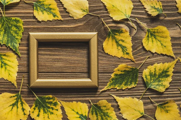 Empty frame and autumn yellow leaves on a wooden background. Thanksgiving holiday concept. Top view. Flat lay.Copy space