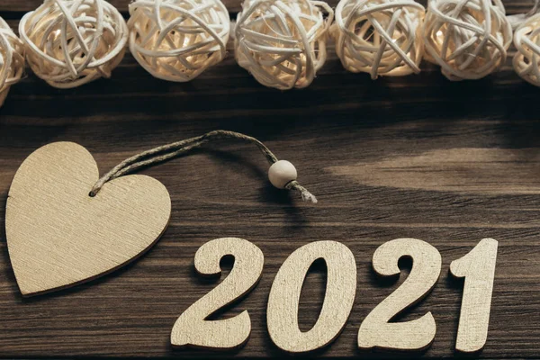 Yeni yıl 2021. Altın sayılar, süslemeler ve koyu ahşap bir masanın üzerinde parıldayan bir çelenk. Mutlu Noeller ve mutlu yıllar. Üst Manzara. Kapat..